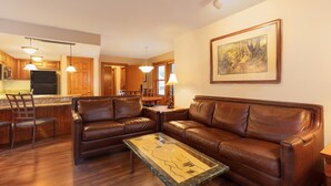 Una sala de estar con un sofá de cuero marrón, una mesa de centro y un comedor con sillas y mesa de madera.