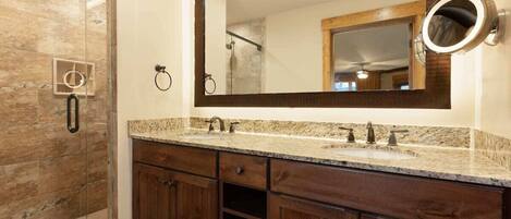 Un baño con cabina de ducha de vidrio, un espejo grande y armarios de madera.