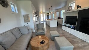 Una sala de estar moderna con un sofá, una mesa redonda de centro y una zona de televisión con chimenea.