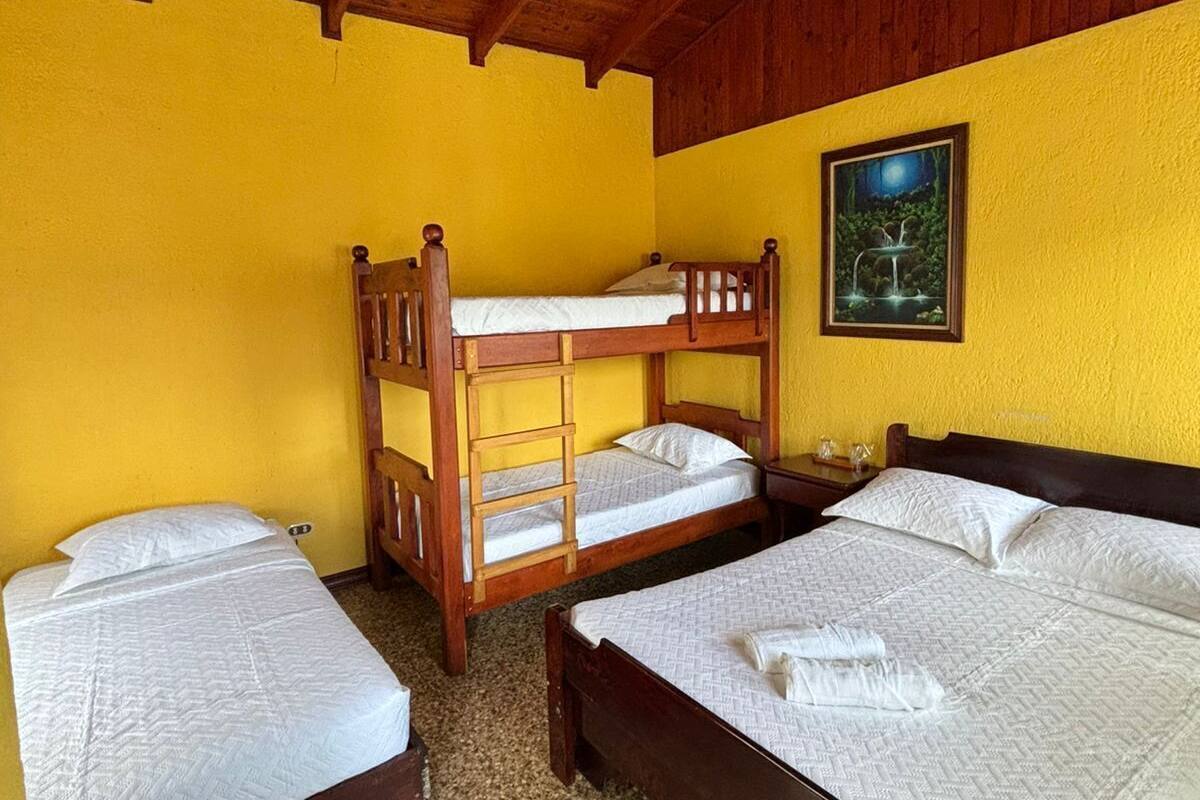 Ein Zimmer mit drei Holzbettklappen, einem Einzelbett und einem Bild an der Wand.