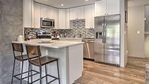 A modern kitchen with white cabinets, stainless steel appliances, and a central island with bar stools.