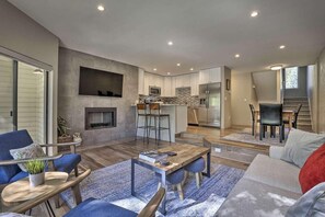 A modern living room with a fireplace, a dining area, and a kitchen with a stone backsplash. - Spacious 4-Bedroom Townhome in Avon, CO (Avon)
