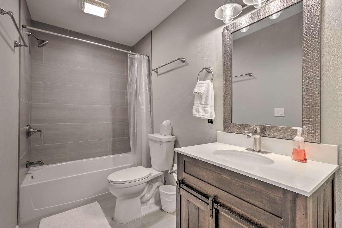 A modern bathroom with a bathtub, toilet, and vanity.