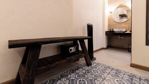 Ein Badezimmer mit einer Holzbank, einem runden Spiegel und einem Waschbecken.