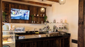 Eine Bar mit Kaffeemaschine, Teeausstattung und Regalen mit Dekoration.