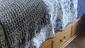 Un dormitorio con cama, cabecera de madera, mesita de noche con lámpara y un respiradero en la pared.