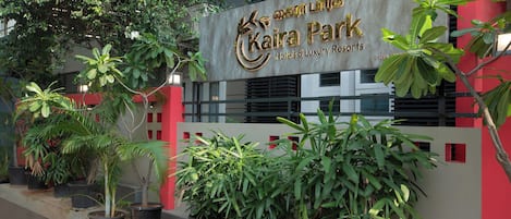 A sign for Kaira Park Hotels & Luxury Resorts with potted plants in front.