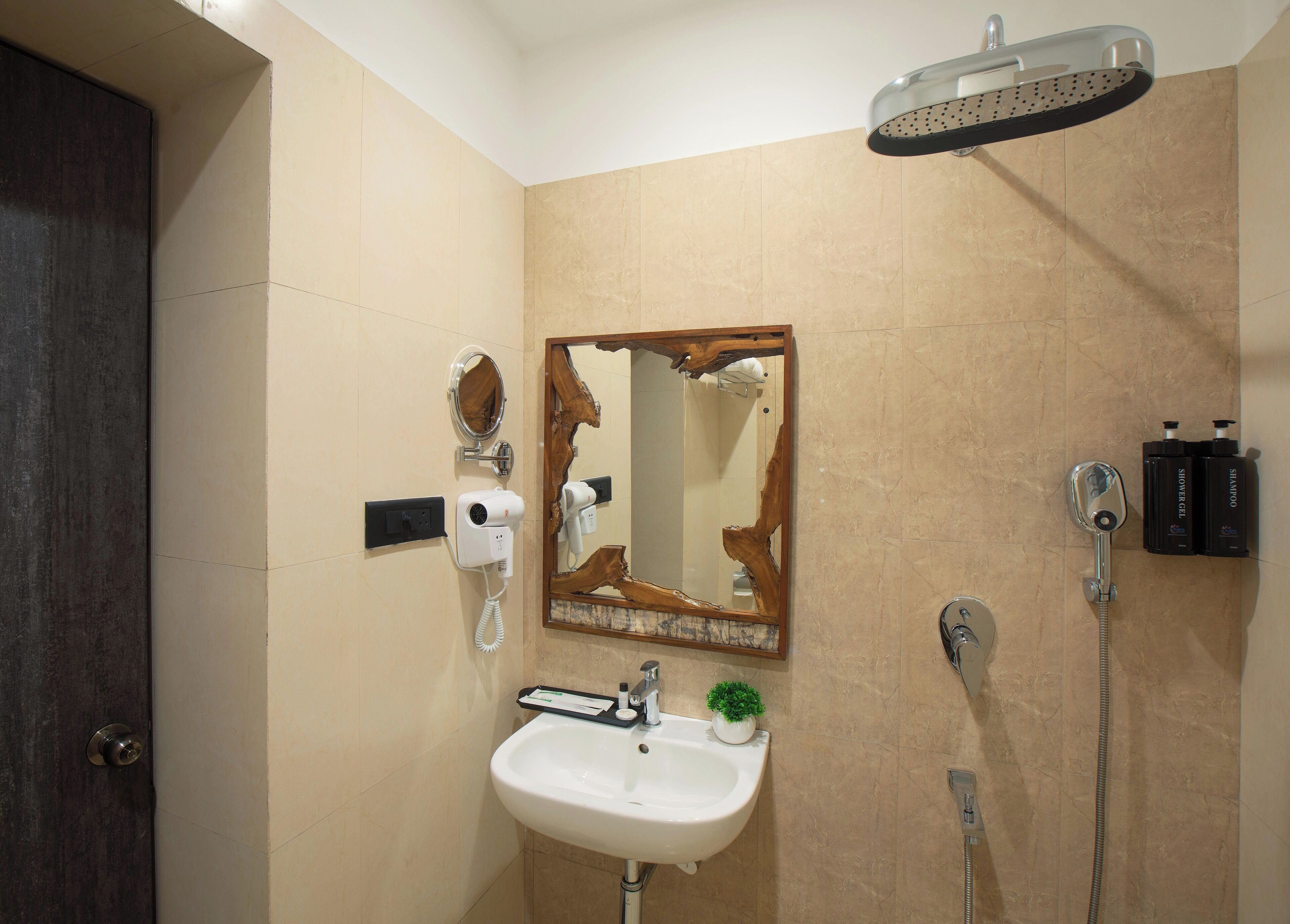 A bathroom with a sink, mirror, hairdryer, shower, and toiletries.
