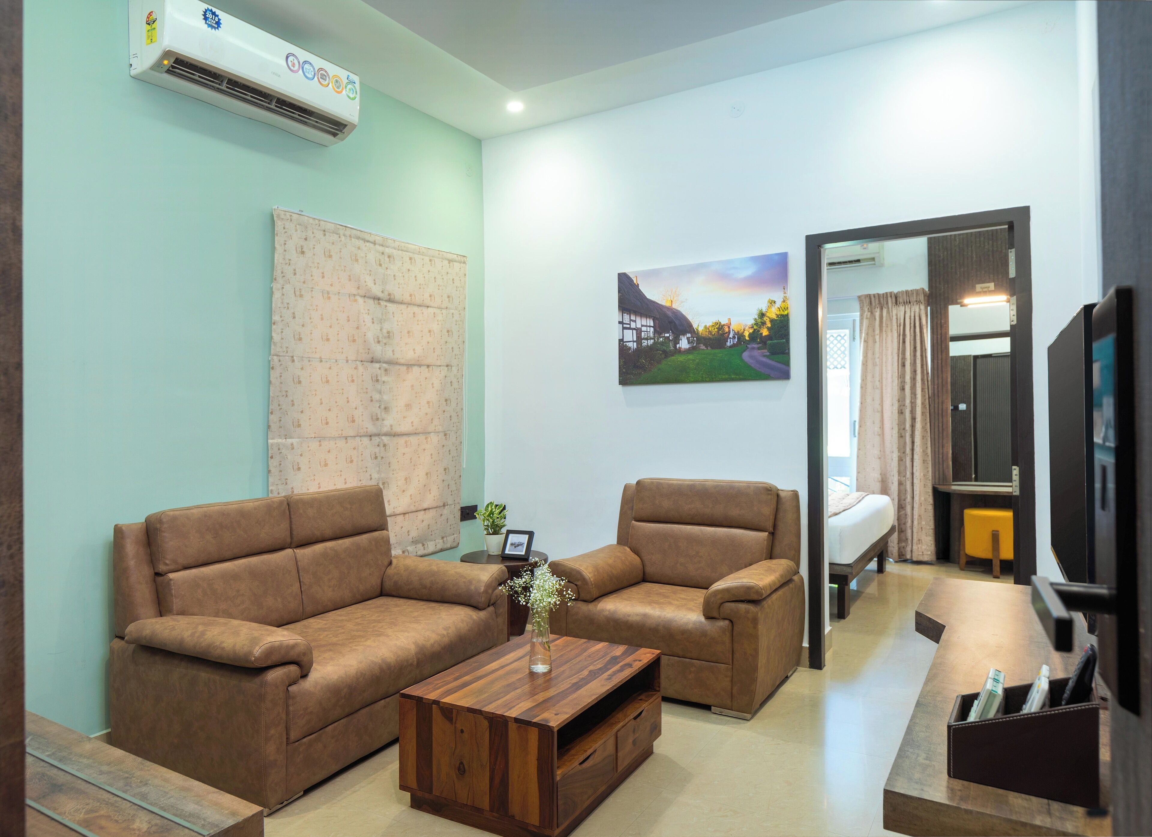 A living room with two brown sofas, a wooden coffee table, and a painting of a village scene.