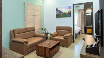 A living room with two brown sofas, a wooden coffee table, and a painting of a village scene.