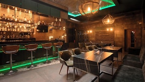 A modern bar area with high stools, a bar counter with bottles, and a seating area with tables and chairs. - KAIRA PARK (Chennai)