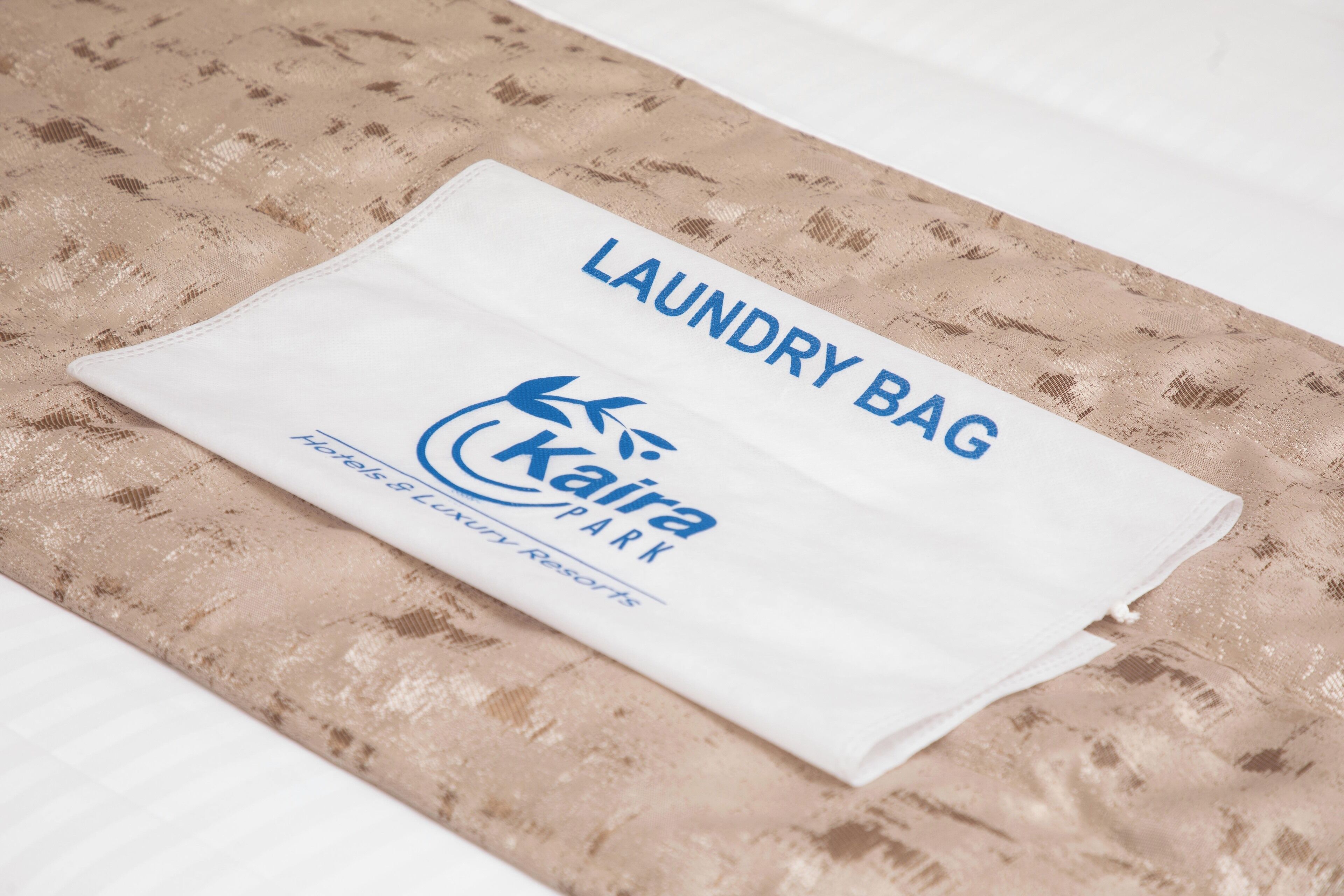 A neatly folded white laundry bag with the text "LAUNDRY BAG" and "Kaira Park" on it.