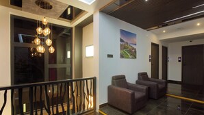 A modern lobby with a chandelier, seating area, and a painting on the wall. - KAIRA PARK (Chennai)