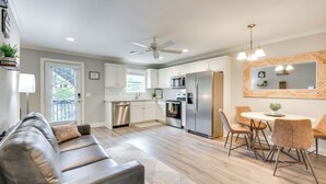 A modern kitchen with white cabinets, stainless steel appliances, and a dining area with a round table and chairs. - Walk to Main St & River: Downtown Helen Condo (Helen)
