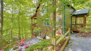 Een vakantiehuis in houtstijl met een veranda, rode Adirondack stoelen en een vuurkorf van steen.