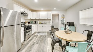 A modern kitchen with white cabinets, stainless steel appliances, and a round dining table with chairs. - 1 Mi to Dtwn: Family Home w/ Porch in Brownwood (Brownwood)