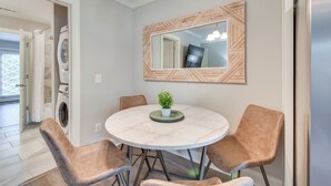 Un coin repas comprenant une table ronde, quatre chaises, une plante en pot et un miroir fixé au mur.