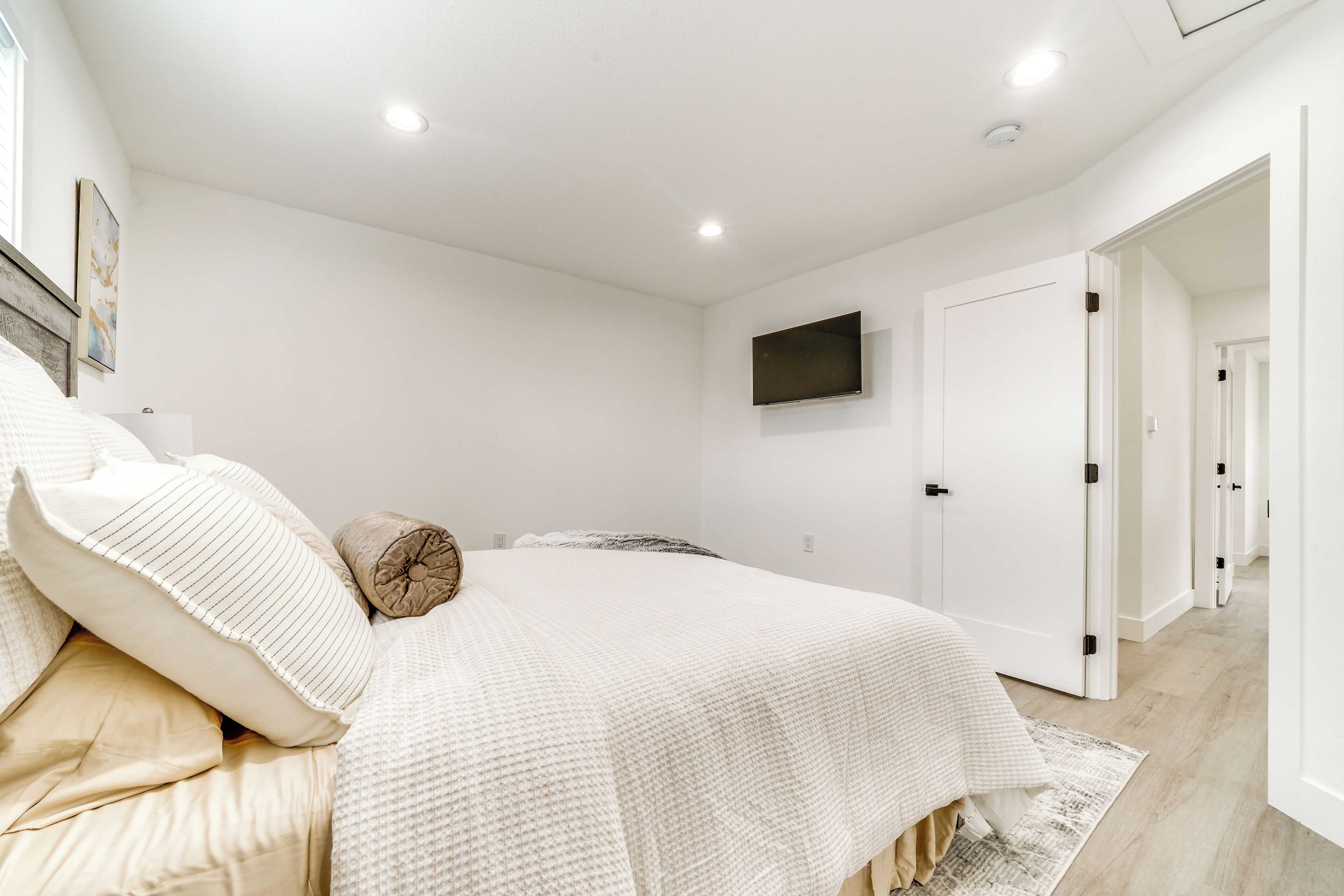 Een slaapkamer met een groot bed, een flatscreen televisie aan de muur en een deur naar een andere kamer.