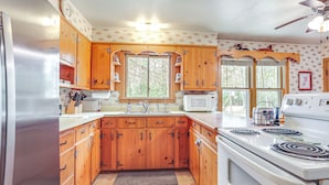 Una cocina con gabinetes de madera, un refrigerador de acero inoxidable, un microondas y una estufa.