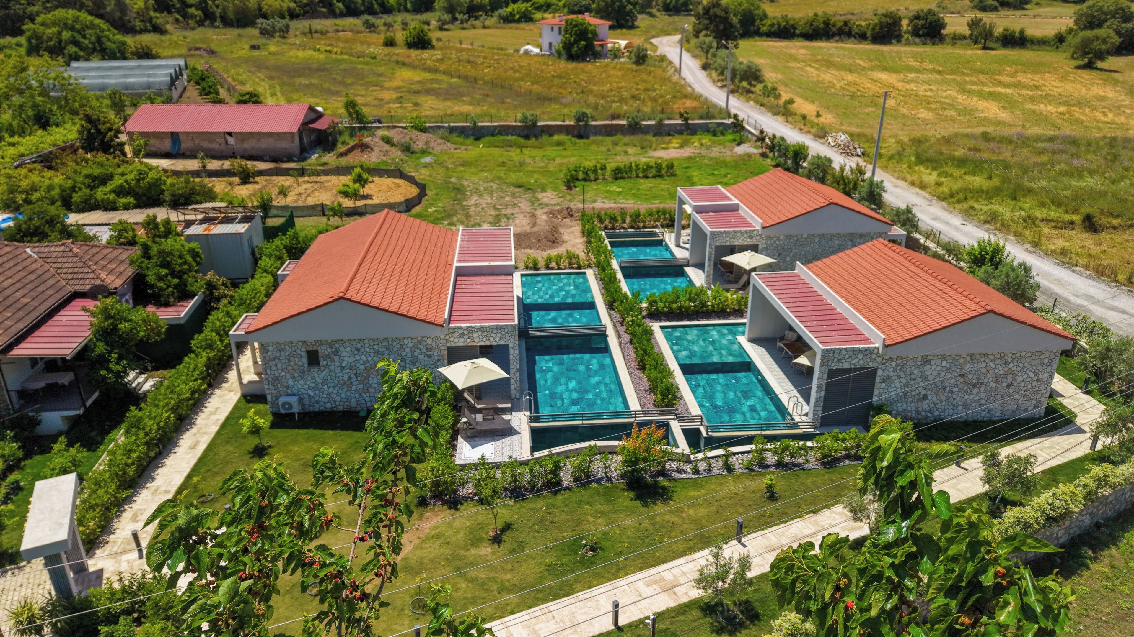 A resort with multiple swimming pools, stone buildings, and a well-maintained lawn.