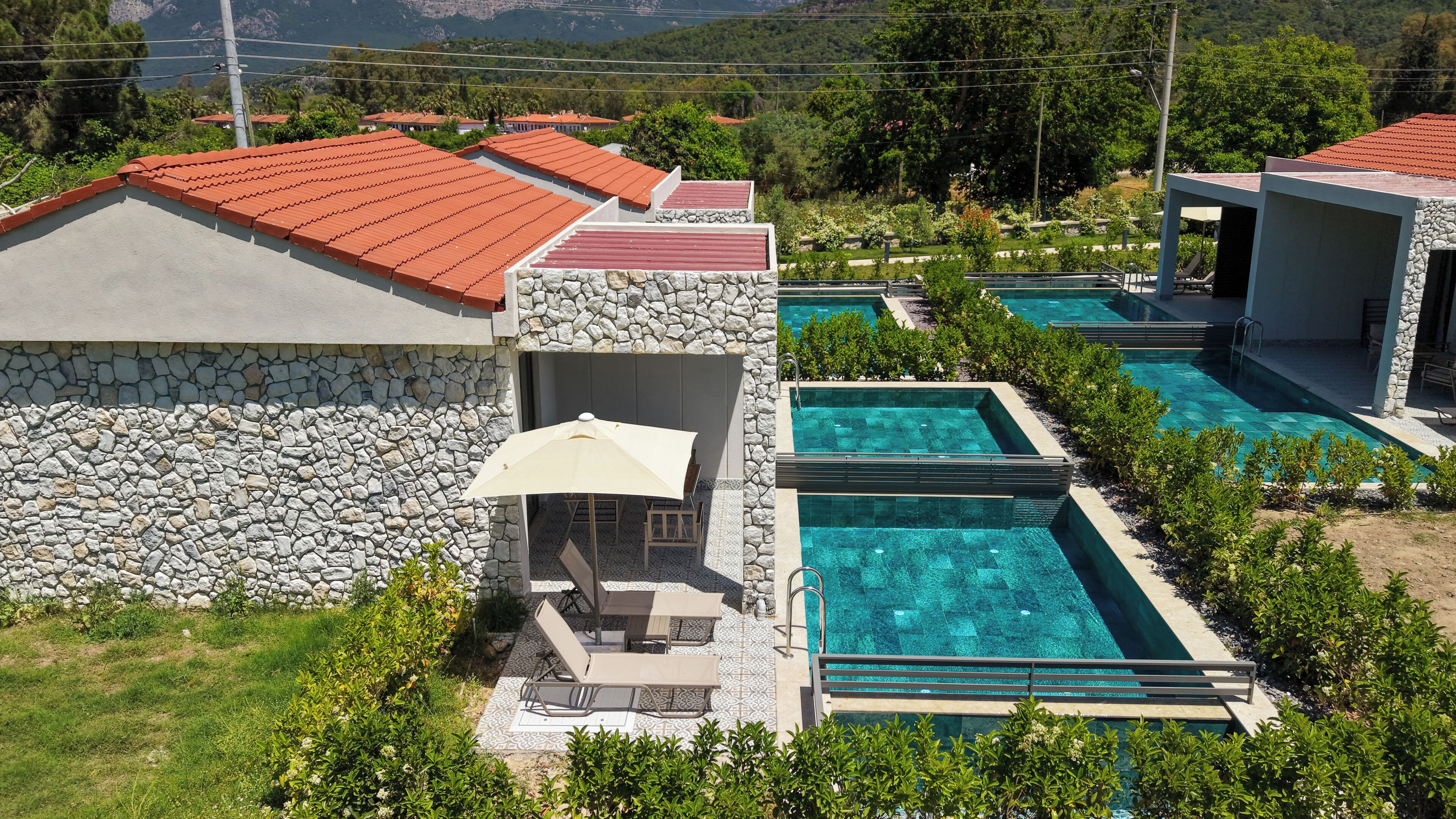 A resort with stone walls, outdoor seating, and multiple swimming pools.