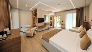 A modern hotel room with a large bed, a seating area, a TV, and a kitchenette. - Casa Dila (Marmaris)