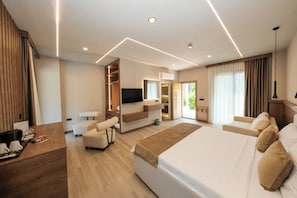 A modern hotel room with a large bed, a seating area, a TV, and a kitchenette. - Casa Dila (Marmaris)