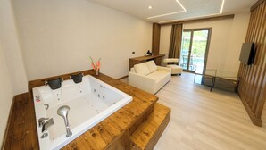 A modern bathroom with a large bathtub, a wooden vanity, and a white sofa in a spacious living area. - Casa Dila (Marmaris)