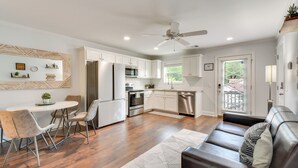 A modern kitchen with white cabinets, stainless steel appliances, and a dining area with a round table and chairs. - Steps to River + Shops: Downtown Helen Retreat! (Helen)
