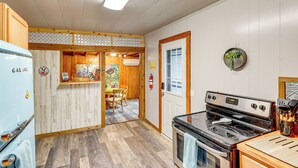 A kitchen with a white refrigerator, wooden cabinets, a stove, and a dining area with a table and chairs. - Deck, Hot Tub & Lake View: Brownwood Home! (Brownwood)