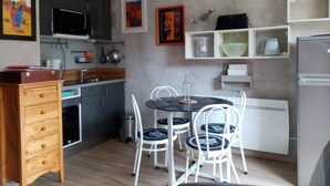 A compact kitchen with a dining area, featuring a wooden cabinet, a microwave, a sink, and a refrigerator. - Near golf course and beaches (Pornic)
