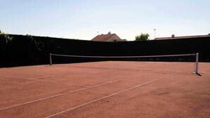 An outdoor tennis court with a net, surrounded by a low wall and a hedge. - Near golf course and beaches (Pornic)
