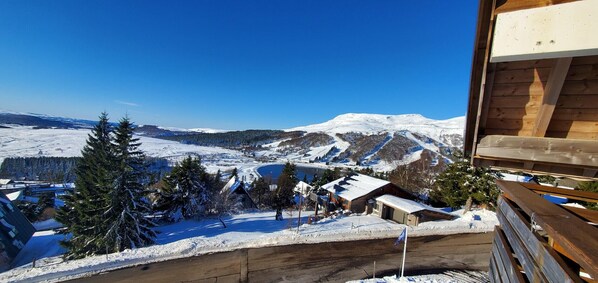Un paisaje nevado de montaña con una cabaña de madera y un cielo azul despejado.
