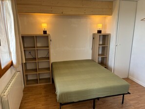 A small room with a single bed, two shelves, and a radiator.