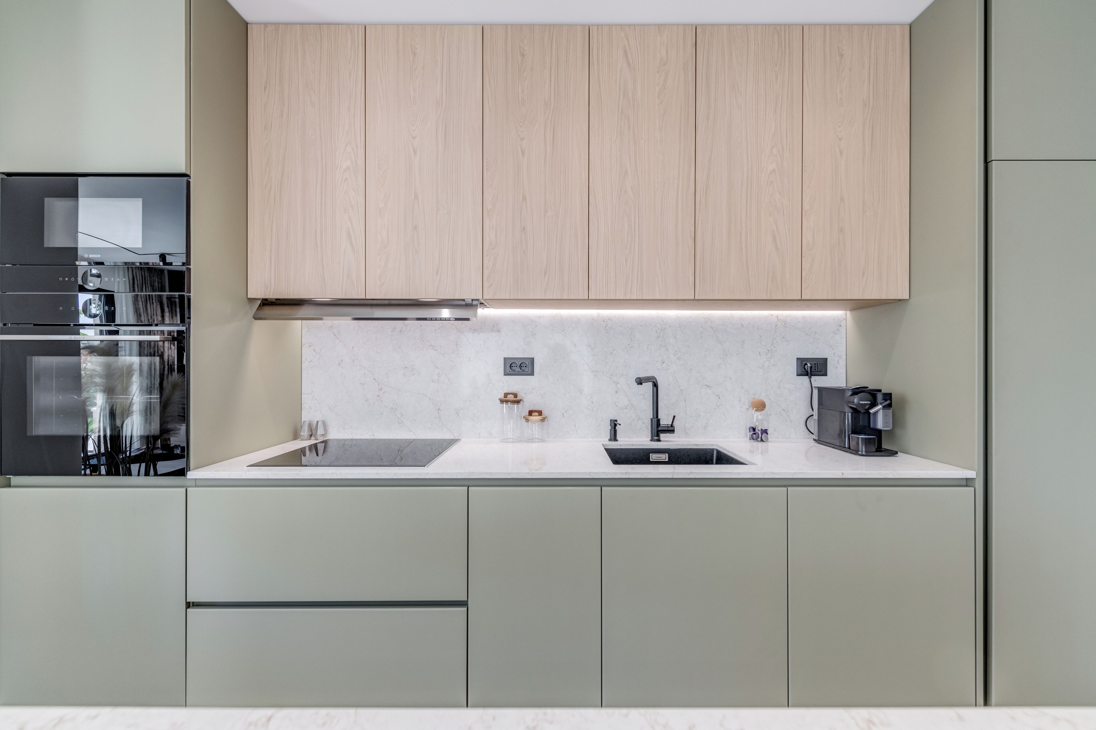 A modern kitchen with a built-in oven, a coffee maker, and a sink.