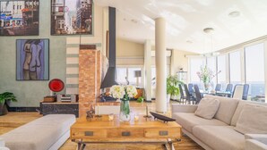 A spacious living area with a fireplace, a dining table with chairs, and a large window offering a view.