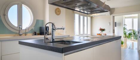 A modern kitchen with a central island, stainless steel appliances, and a large window providing natural light.