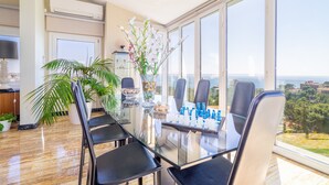 A modern dining area with a glass table, black chairs, and a view of the city.