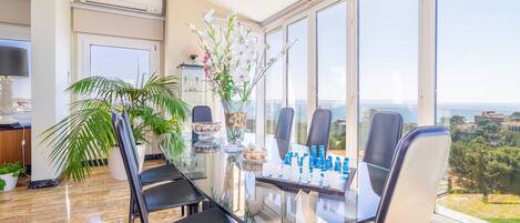 Un área de comedor moderna con una mesa de vidrio, sillas negras y vistas a la ciudad.