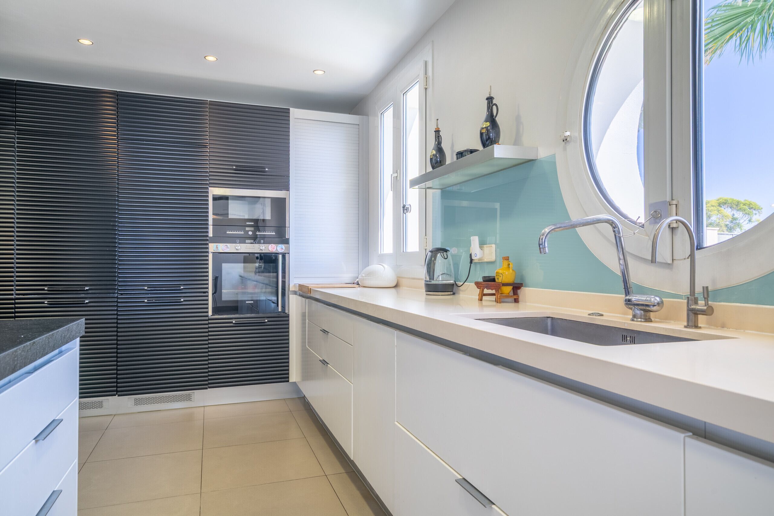 A modern kitchen with a large window, built-in appliances, and a sleek design.