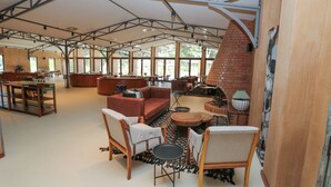 A spacious indoor area with a high ceiling, a brick fireplace, and a variety of seating arrangements including sofas and chairs. - Mumba Lodge by Flow (Cuvango)