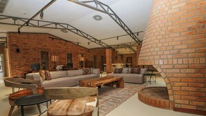A spacious living area with a brick wall, a fireplace, and modern furniture. - Mumba Lodge by Flow (Cuvango)