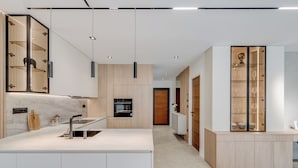Una cucina moderna con isola centrale, elettrodomestici integrati e una vetrina a vetro.