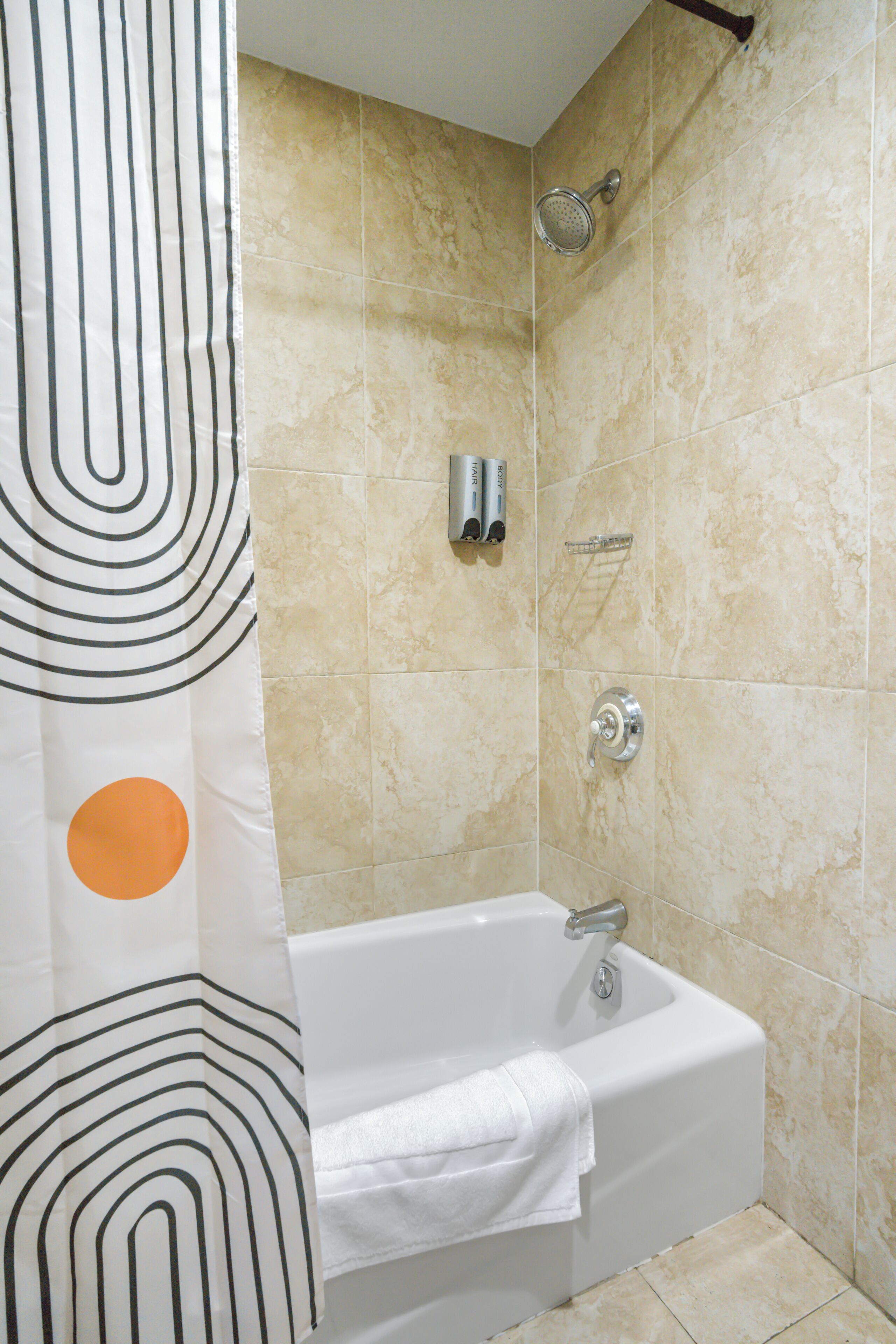 A bathroom with a bathtub, showerhead, and towel rack.