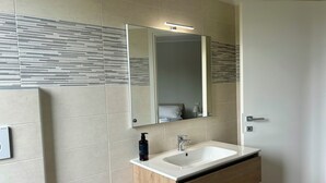 Ein modernes Badezimmer mit Waschbecken, Holzkosmetikschrank und einem Spiegel mit Beleuchtung.