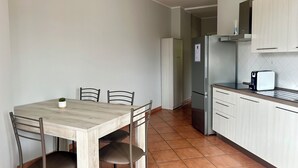 Eine kleine Küche mit Esstisch, Stühlen, einem Kühlschrank und einem Toaster.