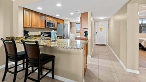 A modern kitchen with granite countertops, wooden cabinets, and stainless steel appliances.