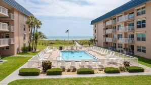 A hotel with a pool area, multiple balconies, and a view of the beach.