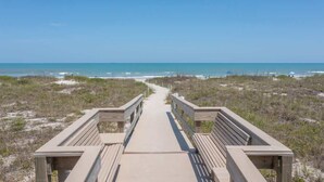 A wooden boardwalk leading to the beach with a clear view of the ocean.