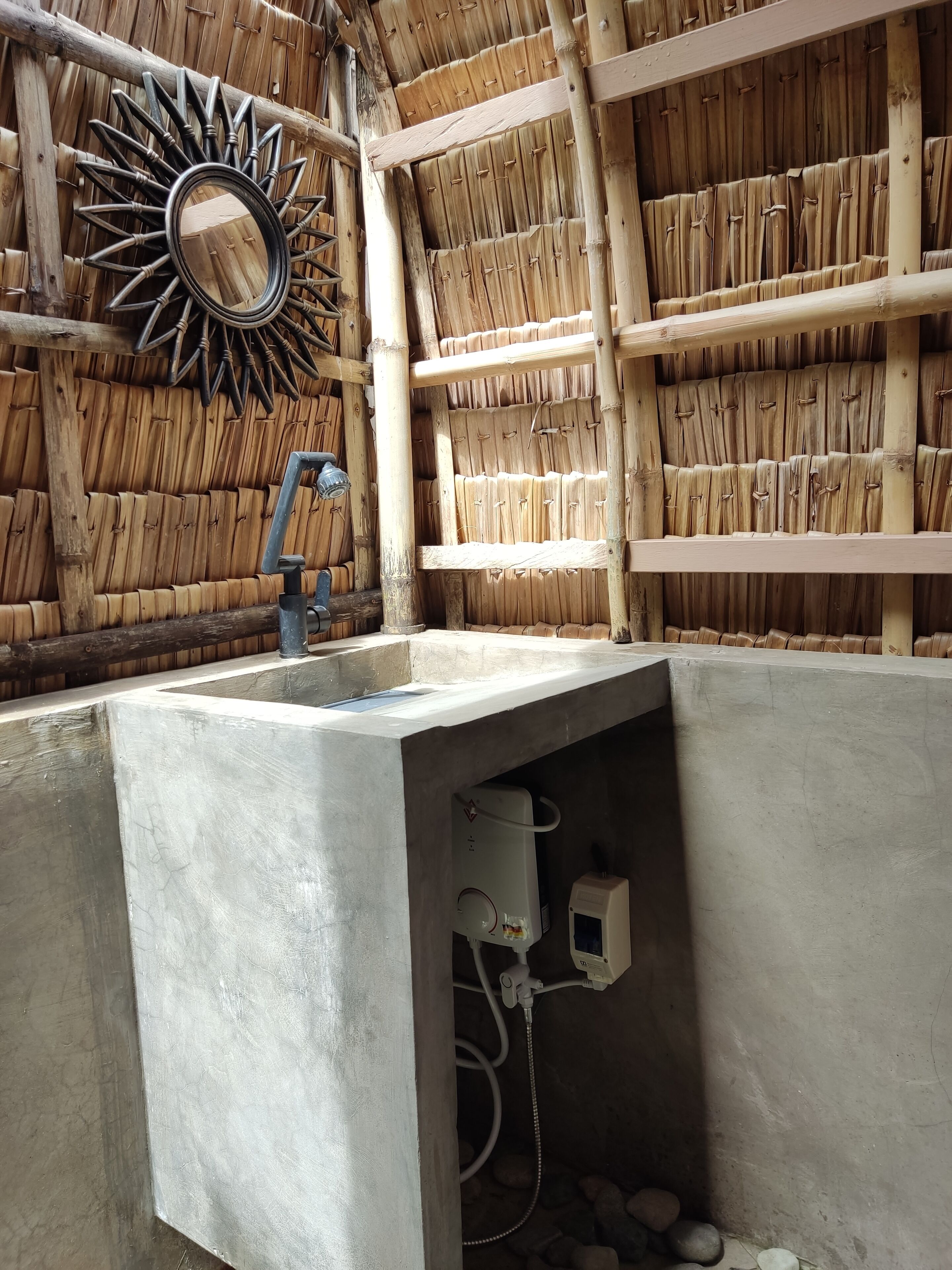 A bathroom with a concrete sink, a mirror, and a shower area.